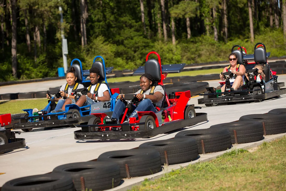 An exterior shot of lively go-kart racing in progress, with participants speeding around a racetrack. The scene is filled with energy and laughter, capturing the excitement of group activities and friendly competition.