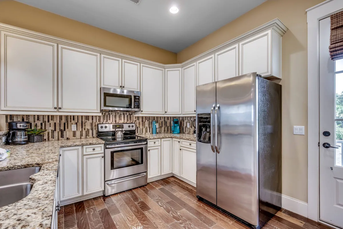 A modern kitchen with stainless steel appliances, granite countertops, a decorative backsplash, and wooden flooring. The space is practical yet stylish, designed for cooking, entertaining, and heartfelt conversations.