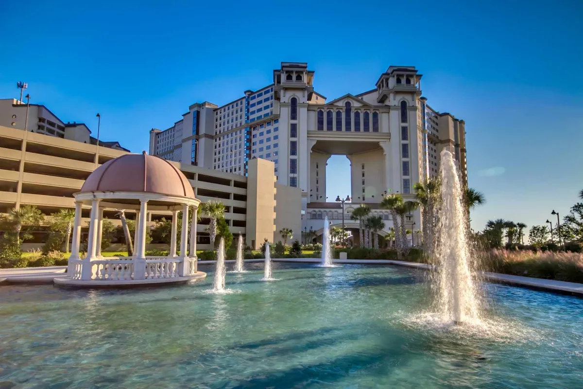 This image shows a serene exterior scene featuring a grand fountain, a charming gazebo, and the elegant architecture of the building in the background. The presence of outdoor spaces designed for relaxation and socializing suggests an upscale, resort-like environment ideal for leisure and gathering with friends.